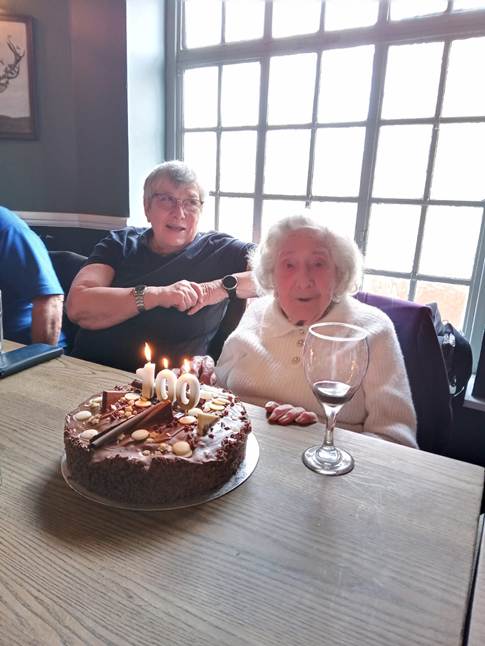 A person sitting at a table with a cake with candles on it

Description automatically generated